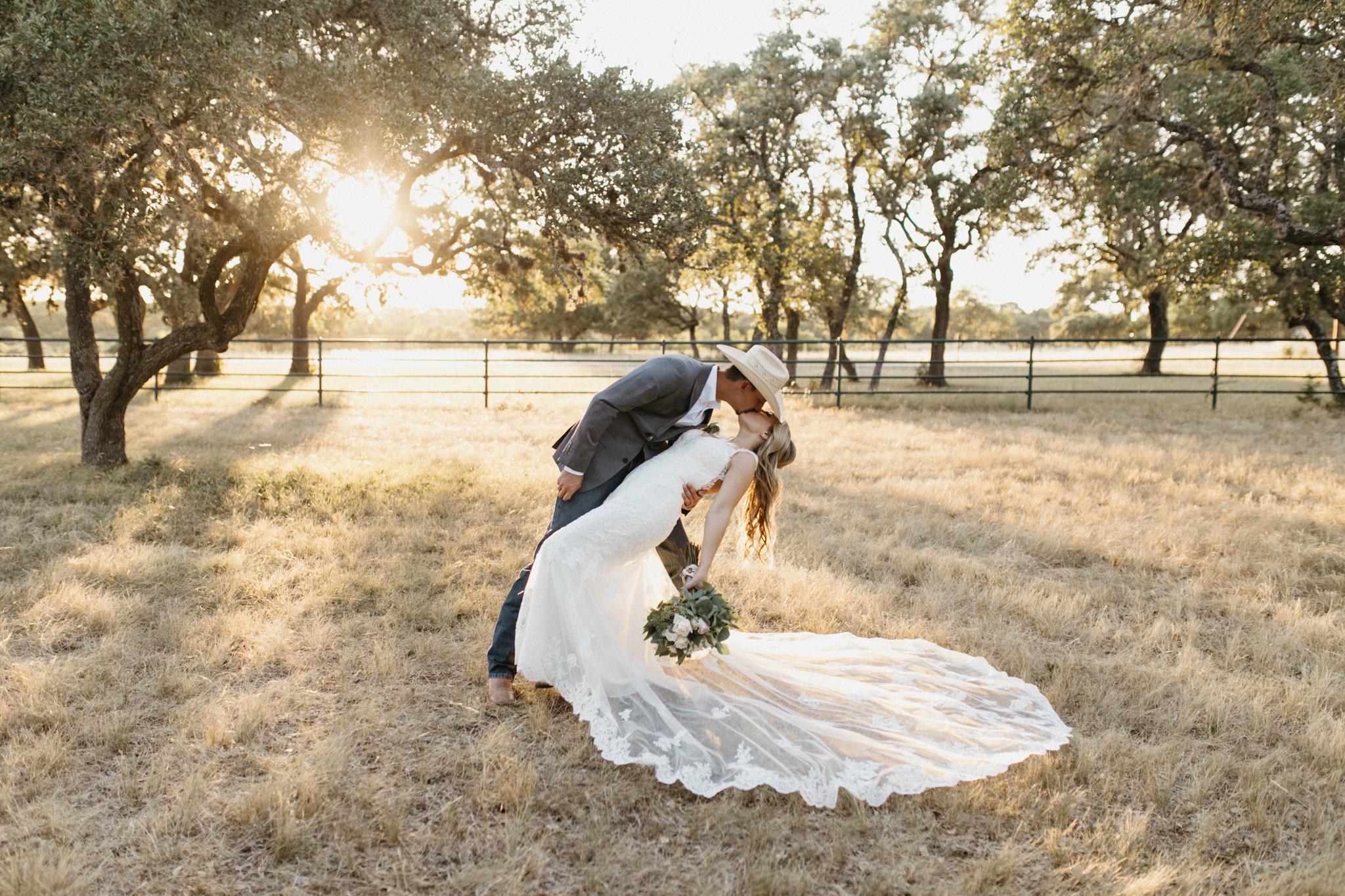 groom dipping bride at sunset at texas ranch