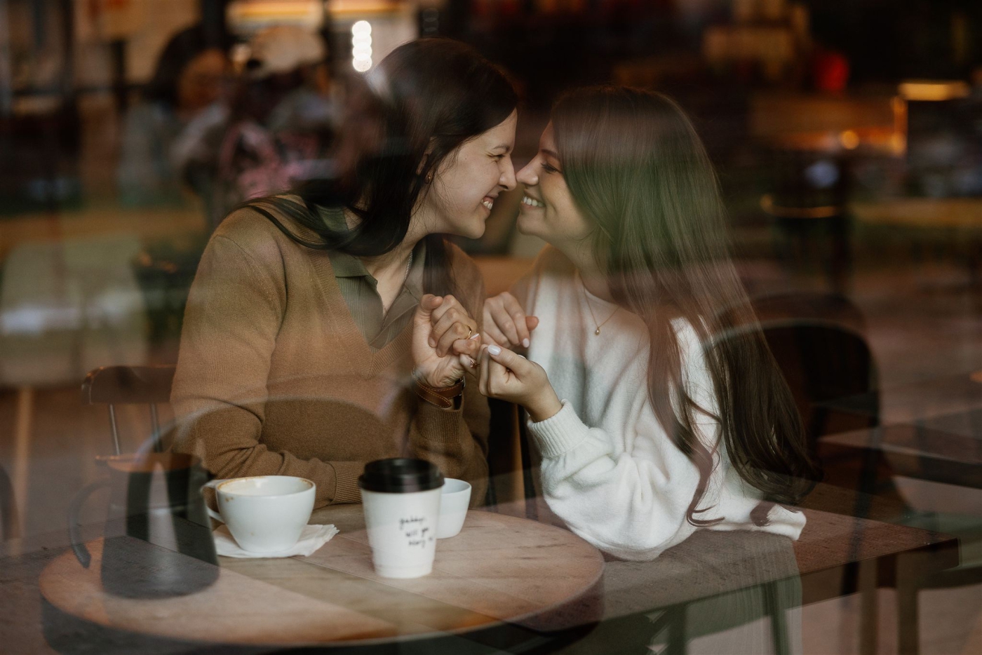 A photo of two women holding hands taken through the window of a coffee shop near the Pearl District in San Antonio